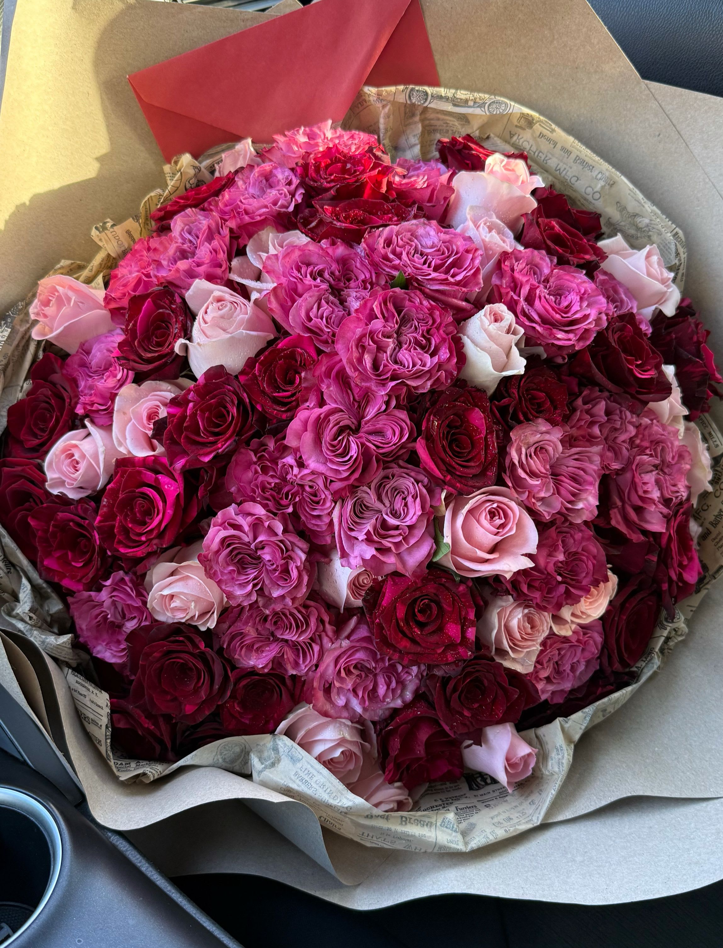 Bouquet of pink, red, and blush roses wrapped in paper