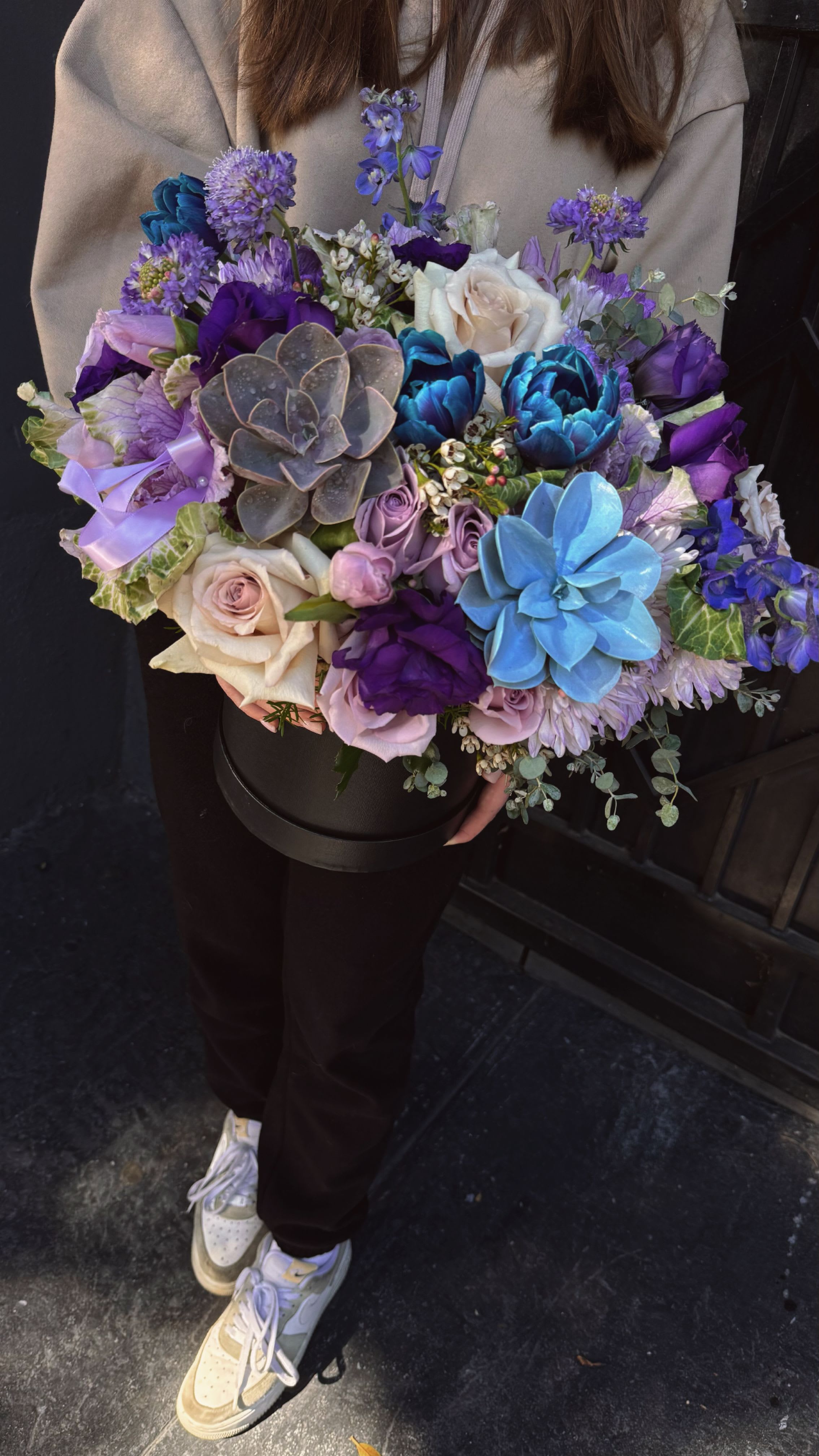 Large bouquet of purple, blue, and white flowers in a black box