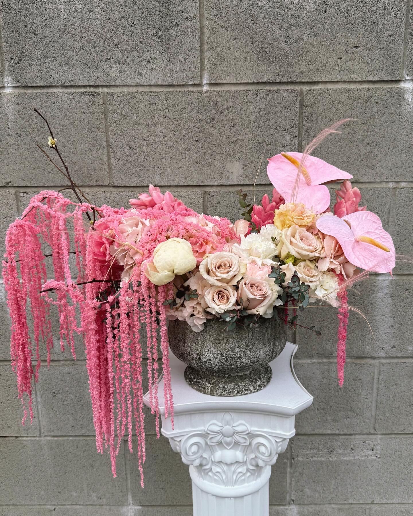 Pink floral arrangement in a stone urn with cascading blooms
