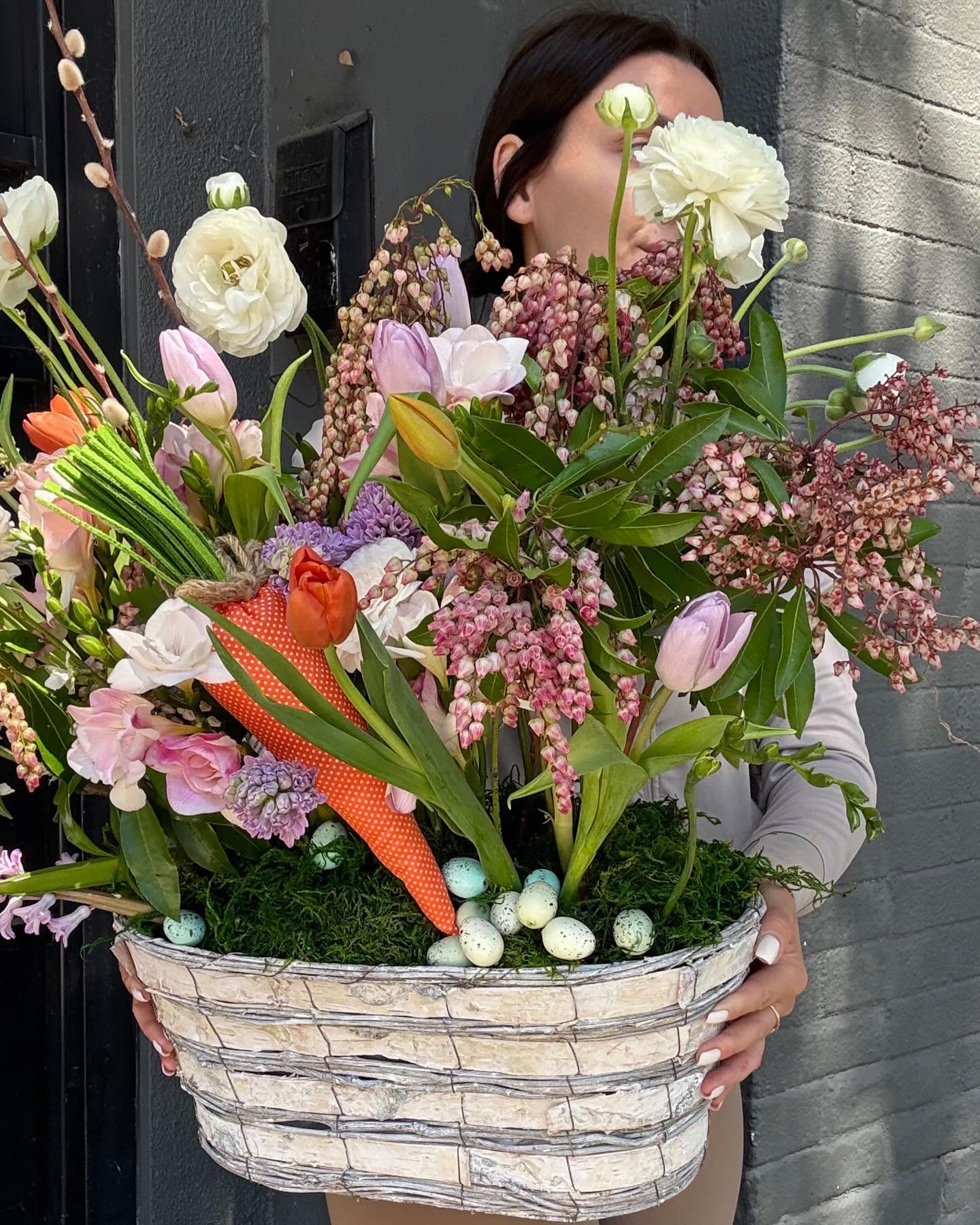 Large spring bouquet in a woven basket with pastel flowers and speckled eggs