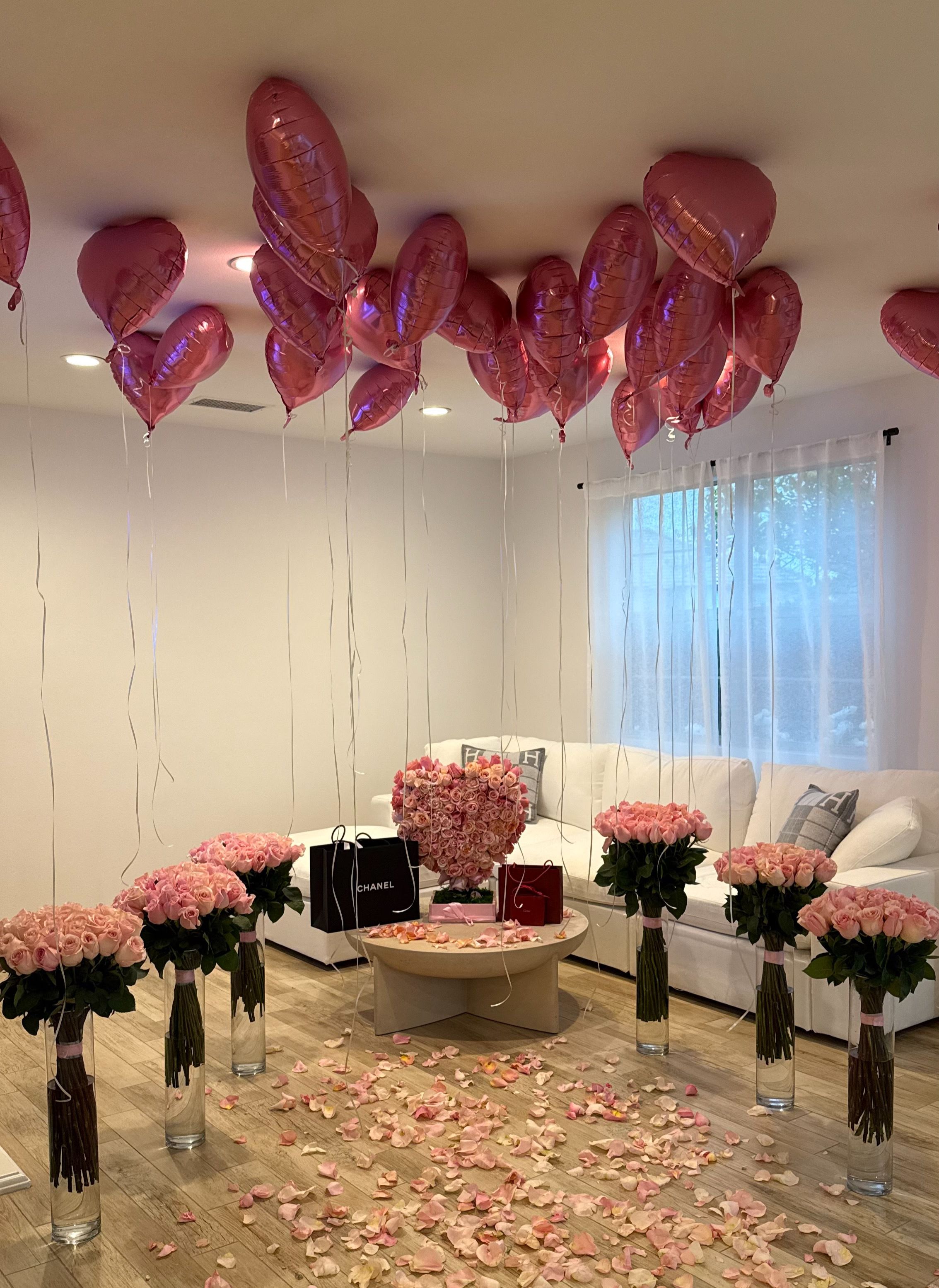 Pink rose arrangements with heart balloons in a living room