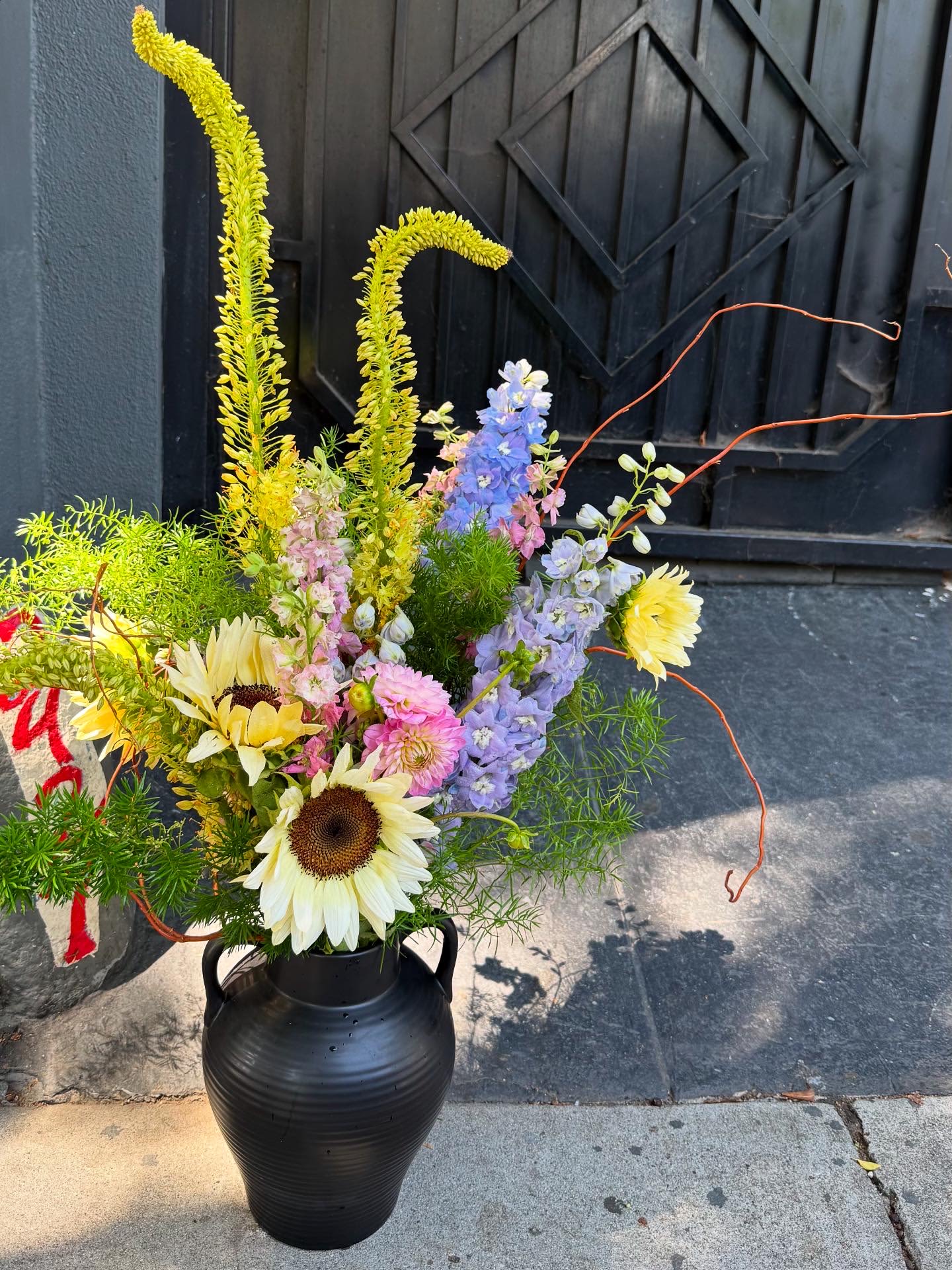 Tall mixed bouquet in a black vase with sunflowers and pastel blooms