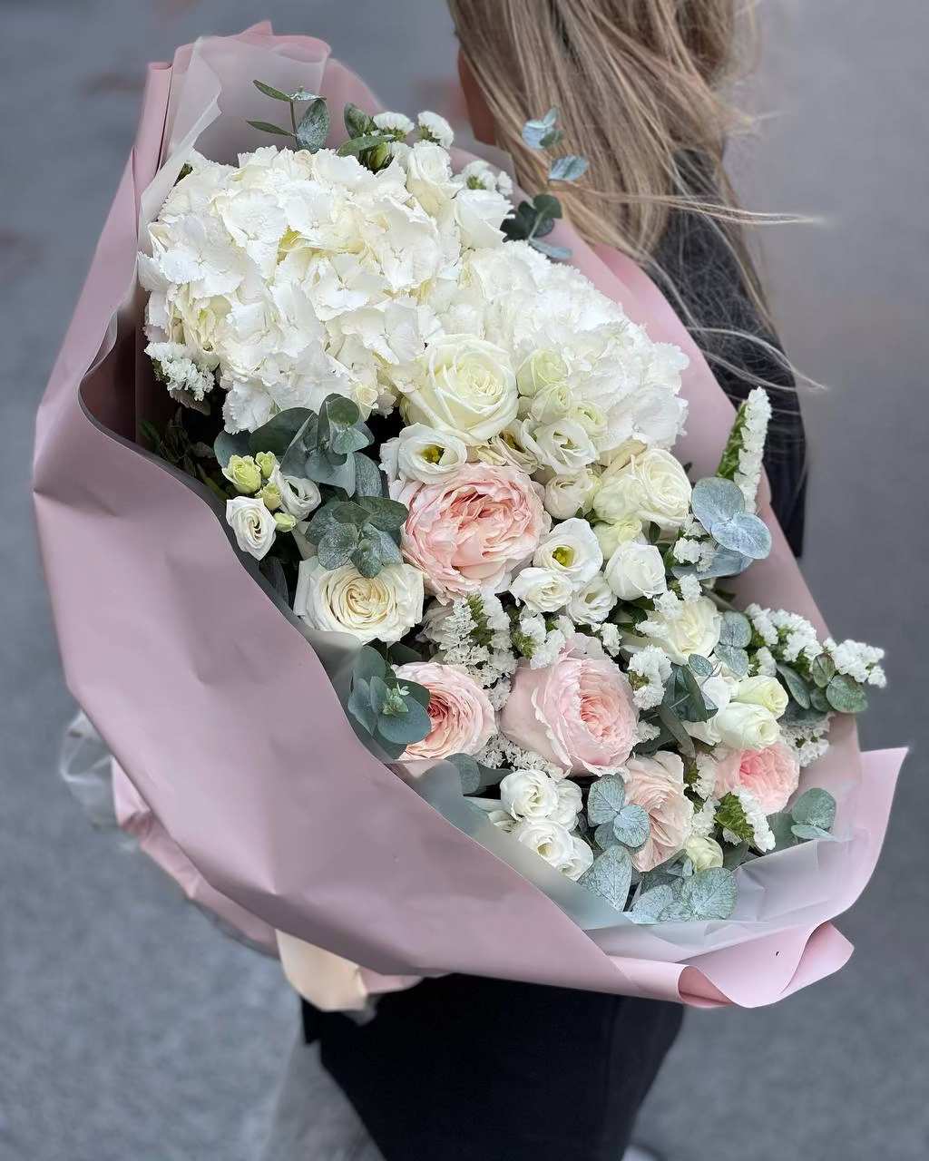 Large bouquet of white and blush flowers wrapped in pink paper