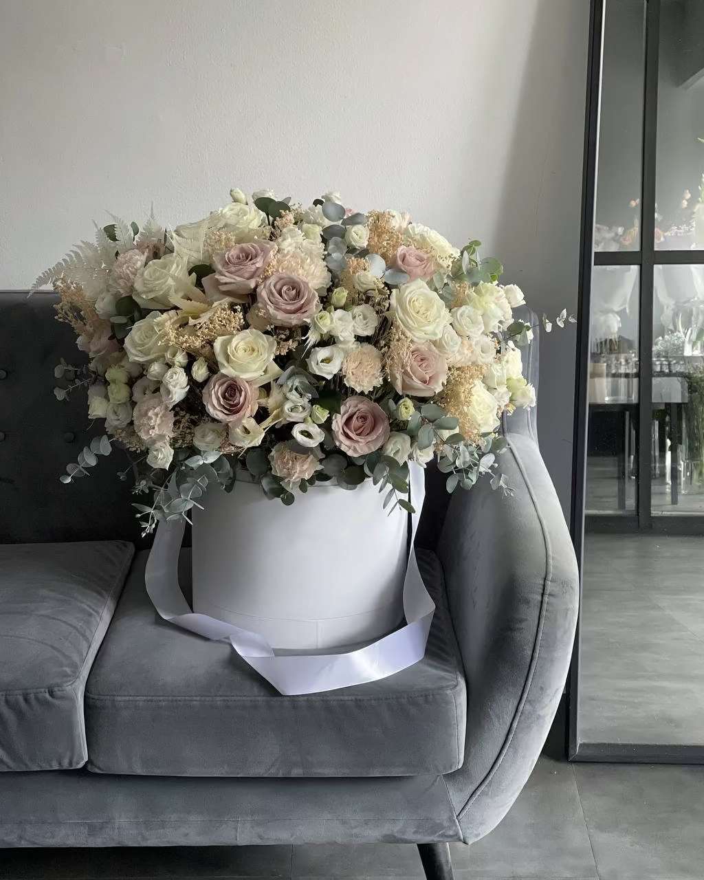 Large pastel flower arrangement in a white hatbox with a ribbon