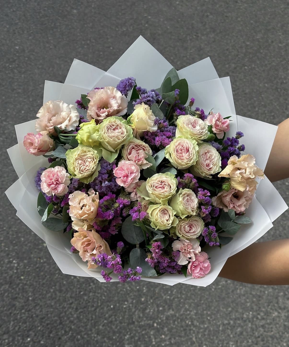 Bouquet of pale roses and pink carnations with purple filler flowers
