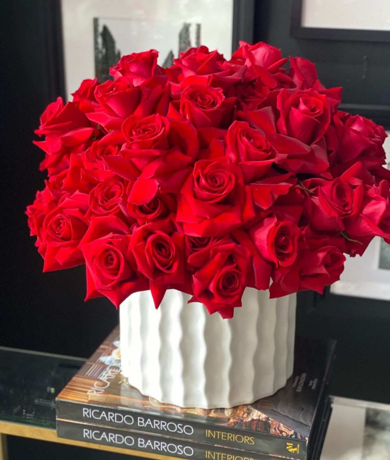 A bouquet of red roses in a white ribbed vase