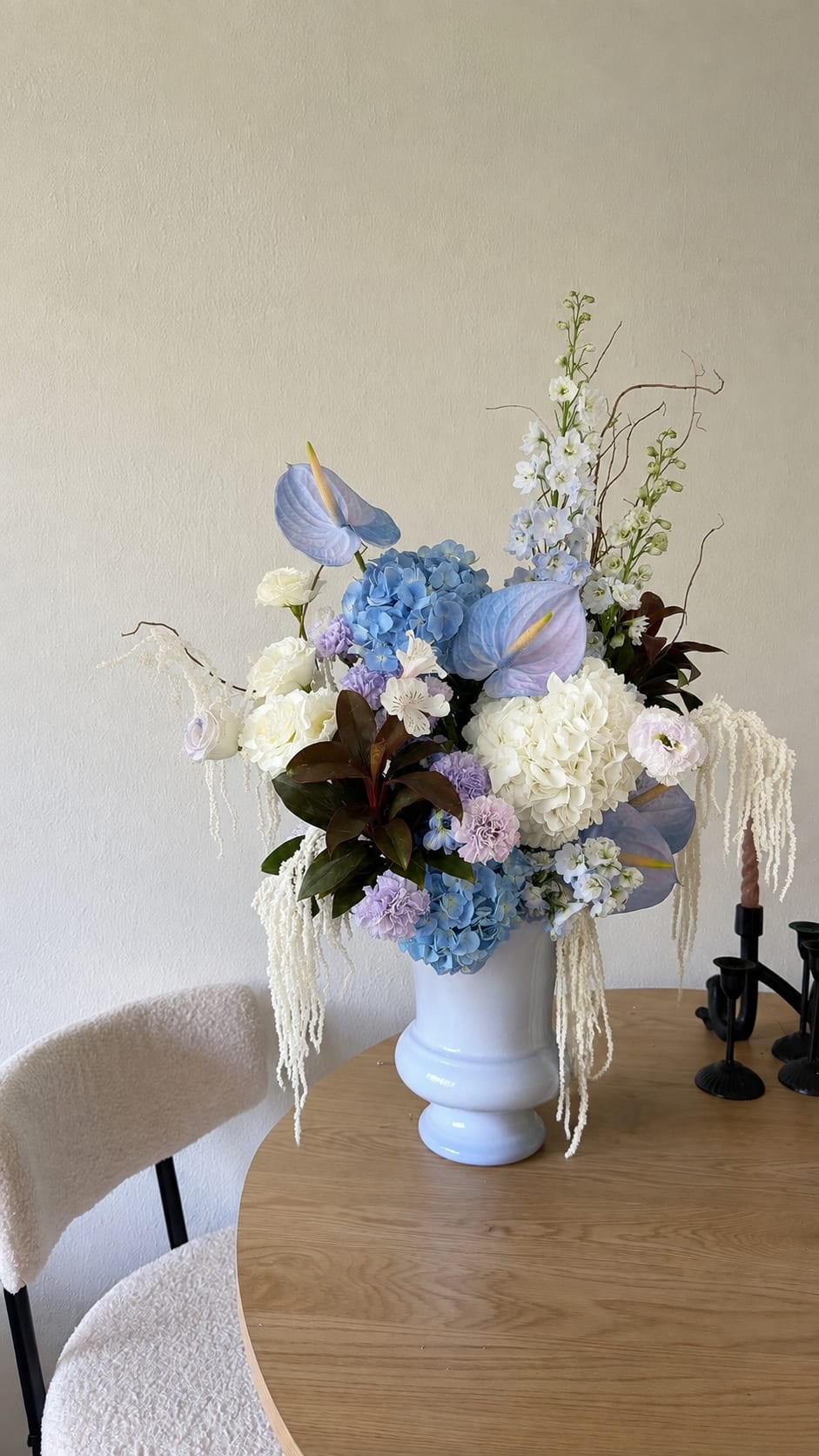 Large pastel floral arrangement in a white vase on a table