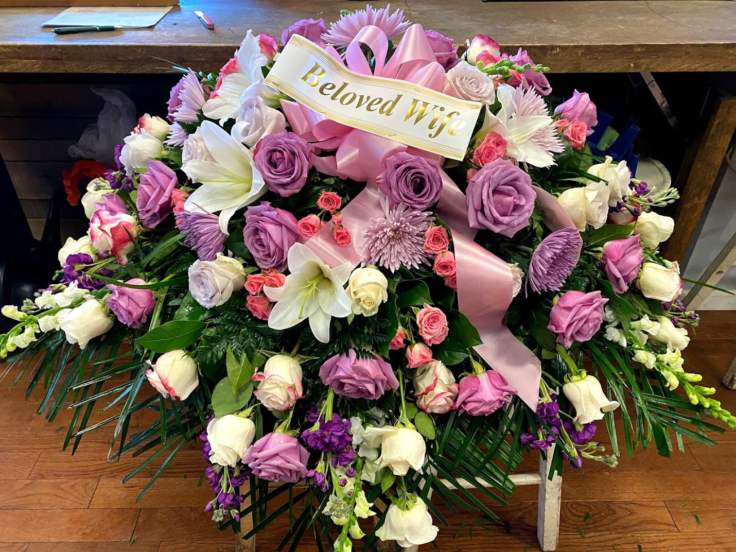 Large pink and white floral spray with a ribbon reading Beloved Wife