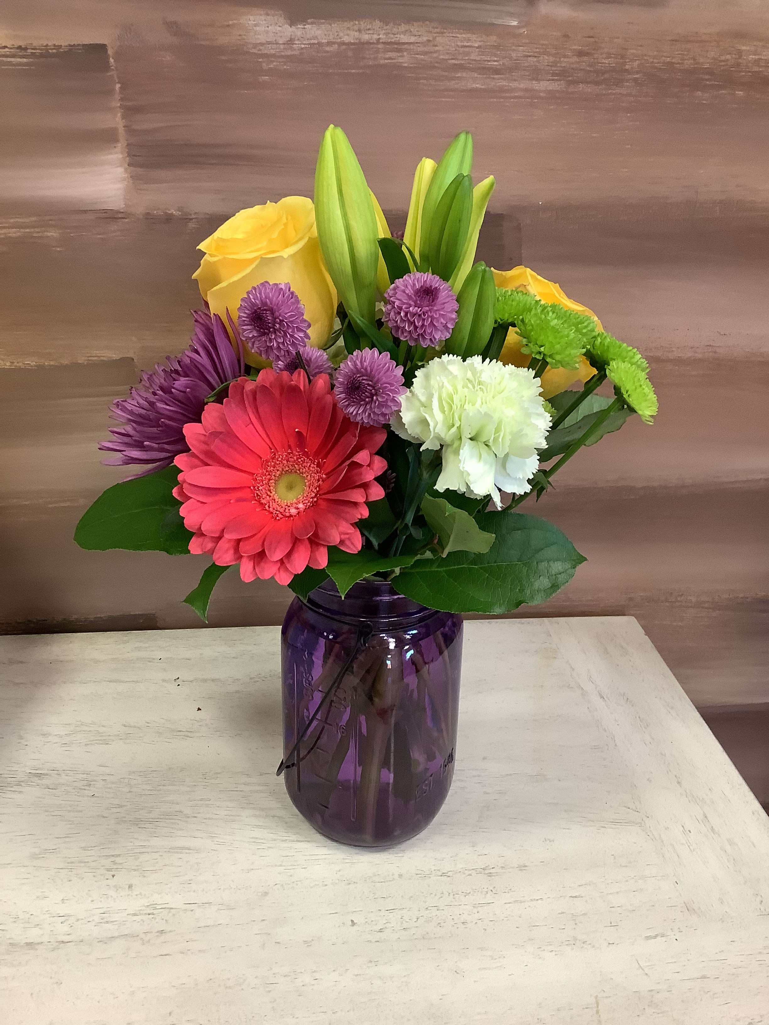 Farmers Picks - This adorable mason jar is filled with some favorites such as gerbers, roses, lily, daisies and whatever blooms are fresh and fun!  This colorful assortment of florals is a fan favorite designed in a glass vase and filled with florals such as hydrangea, roses, stock, lilies and gerbers!   ** Colors and container may vary due to market availability, but we will design to greater or equal value!**