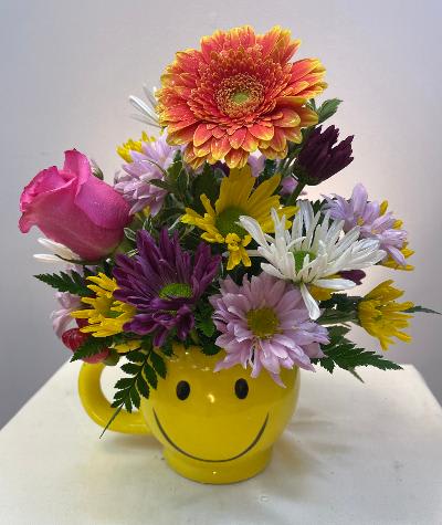 Colorful mixed bouquet in a yellow smiley-face mug
