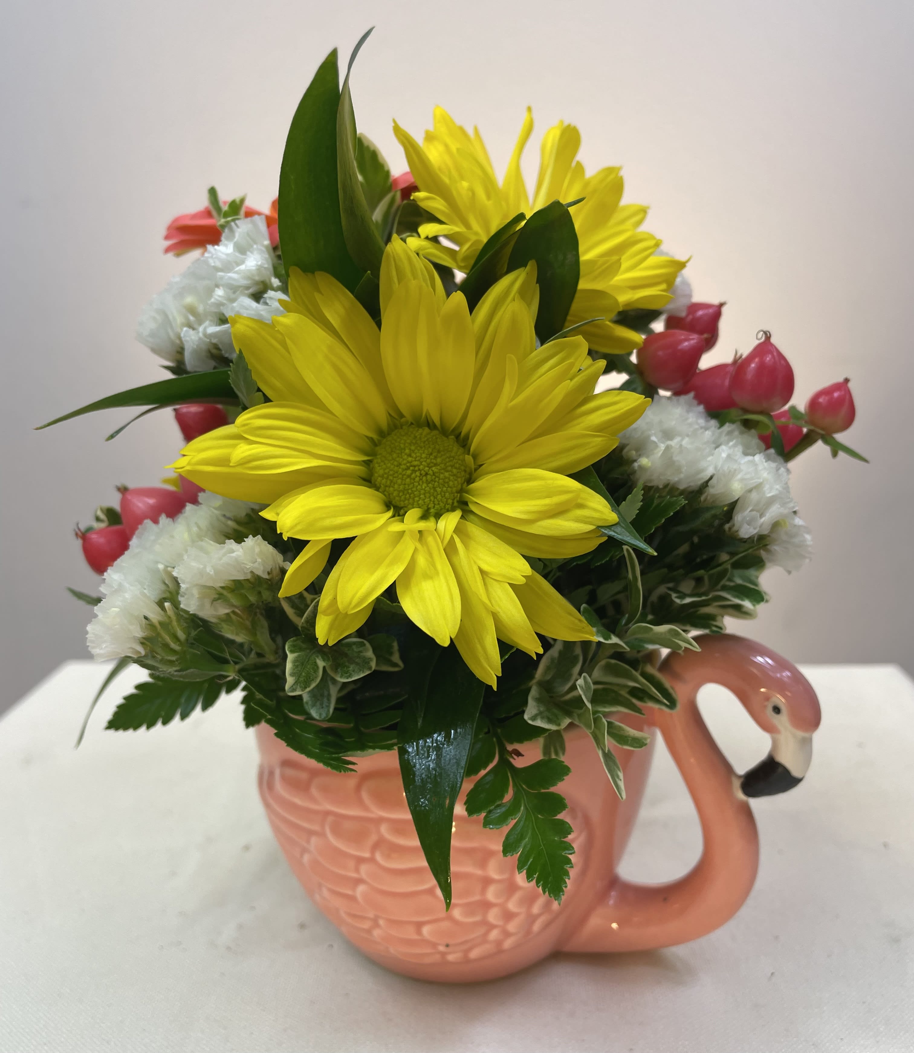 Yellow daisies and pink buds arranged in a flamingo mug