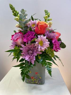 Mixed bouquet of pink and orange flowers in a gray vase