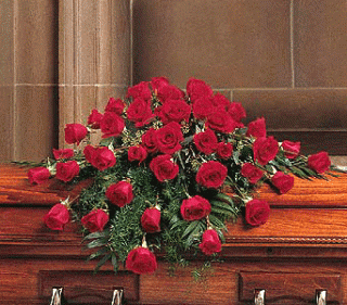 Red rose casket spray arranged across a wooden casket