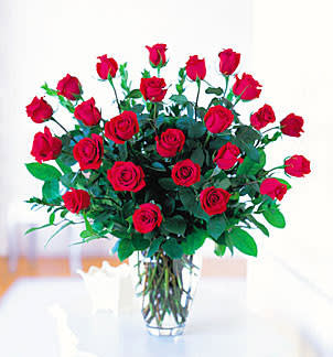 Tall arrangement of long-stem red roses in a clear glass vase