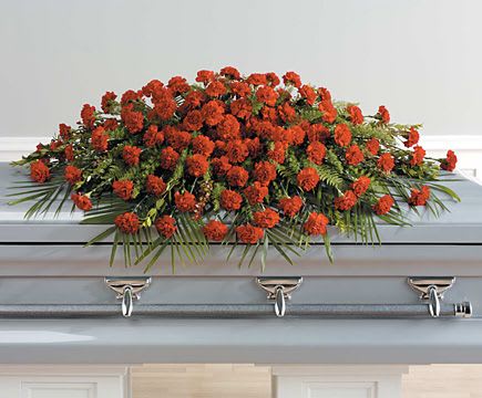 Red carnation casket spray with palm fronds on a light gray casket
