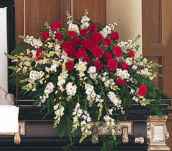 Red and white casket spray with red carnations and white flowers on a dark casket