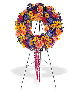 Vibrant multicolor wreath of roses, carnations, and daisies displayed on a standing easel