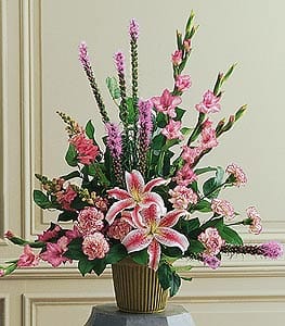 Tall pink floral arrangement with lilies and carnations in a gold-tone container.