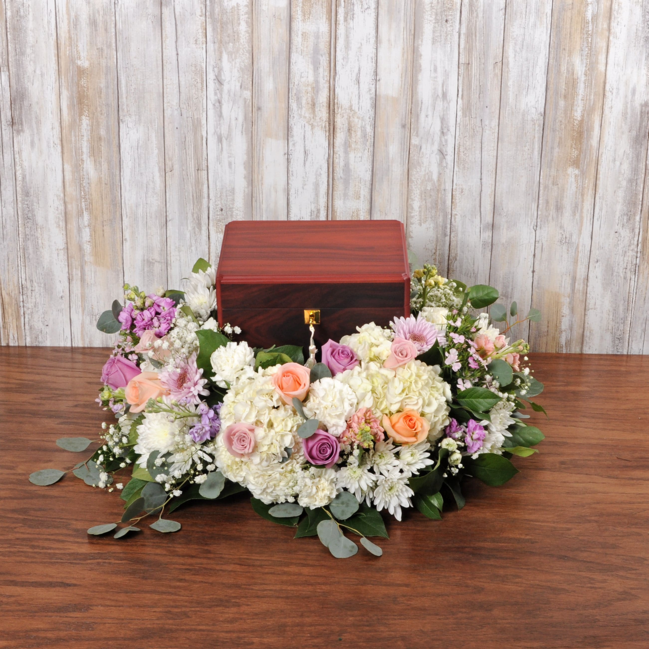 Cremation urn surrounded by a low wreath of white and pastel flowers