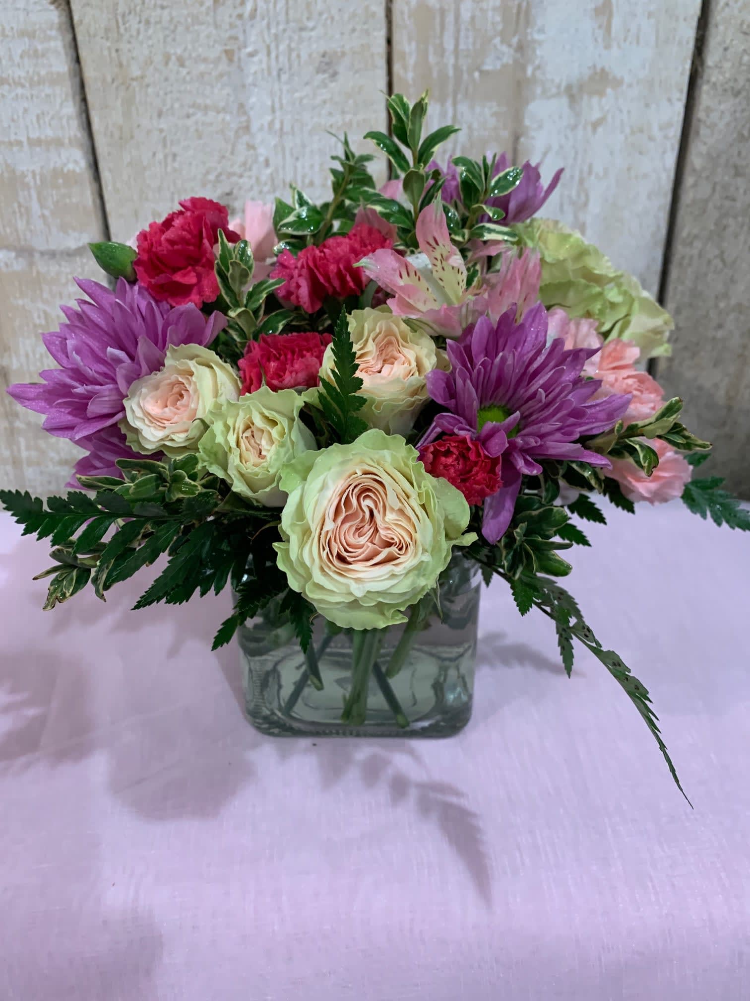 Bouquet of pink and purple flowers in a square glass vase