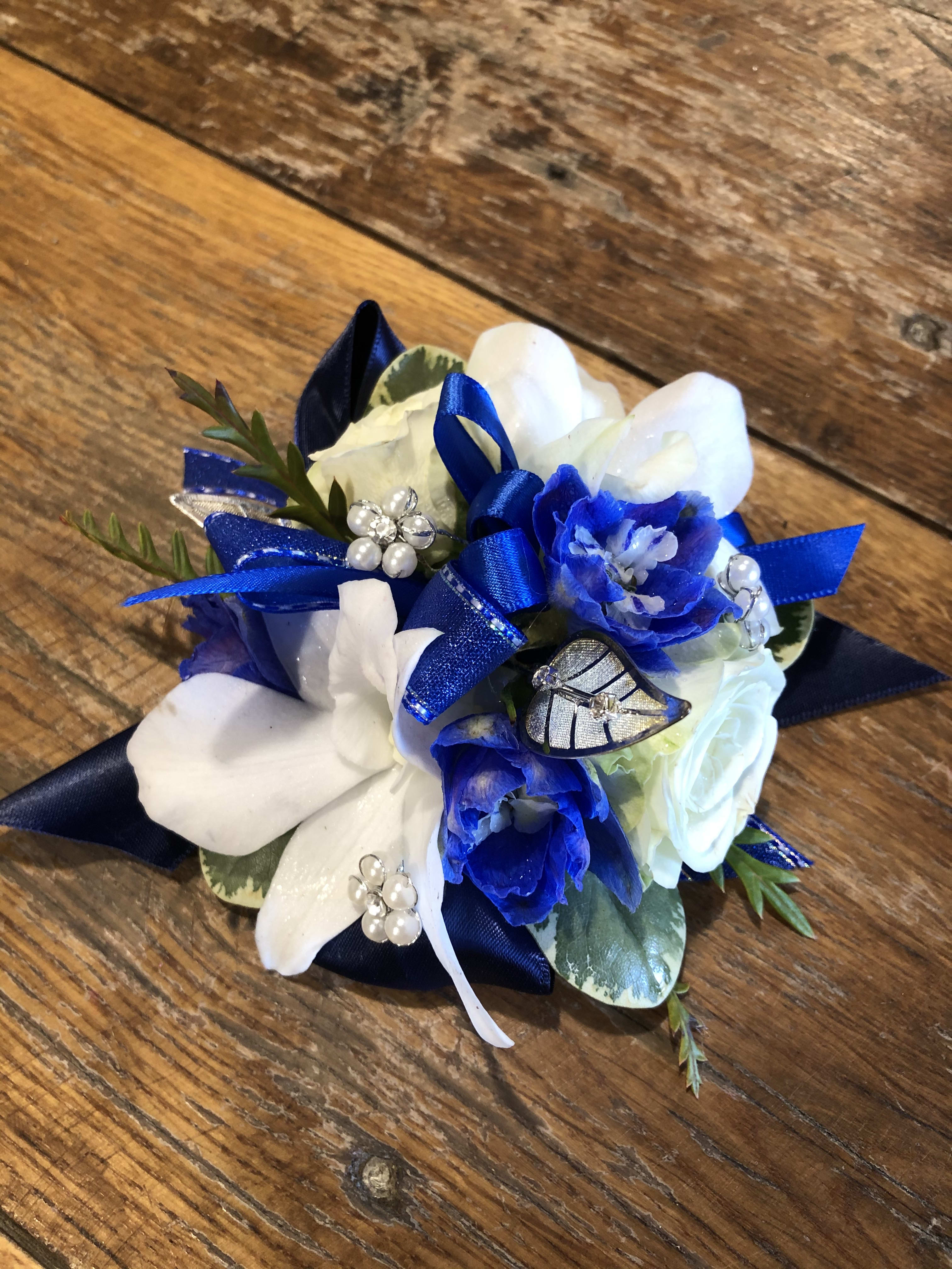 Blue and white floral corsage with ribbon and pearl accents