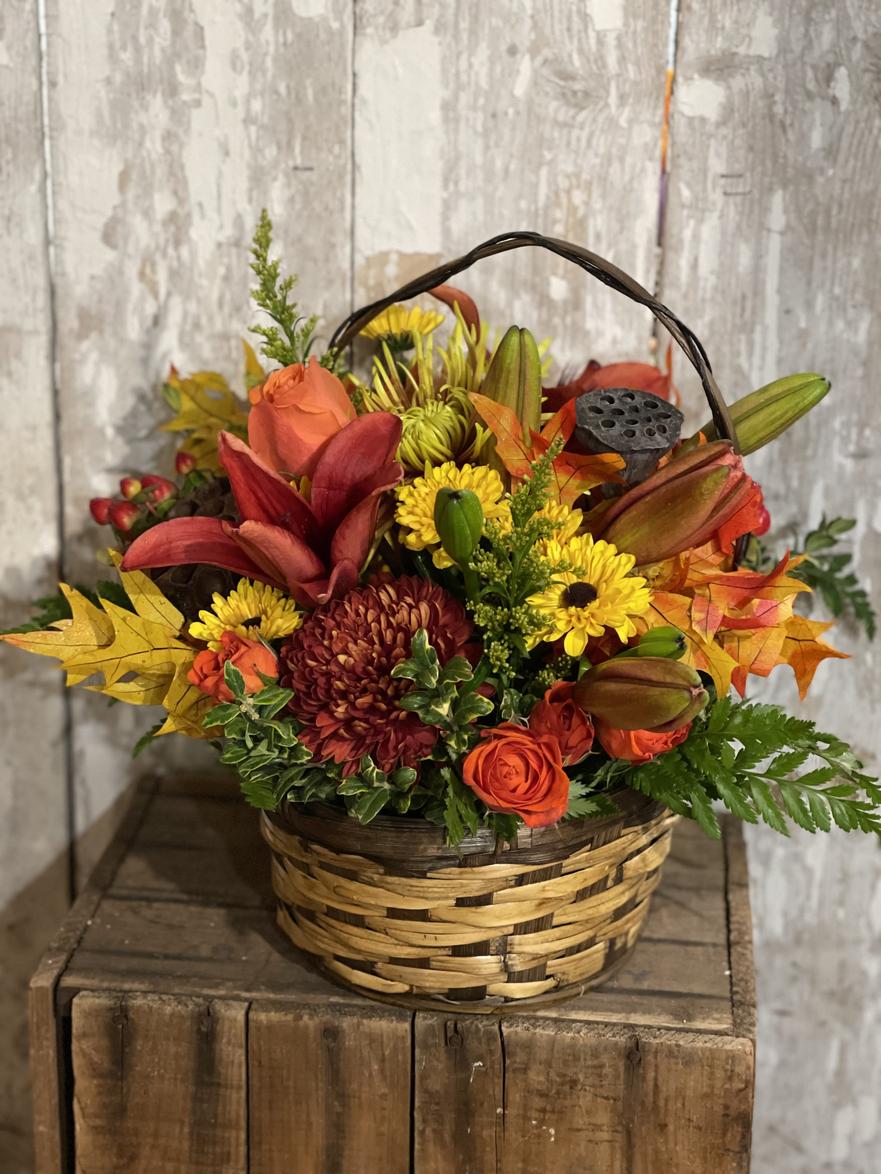 Autumn flower basket with orange roses and yellow mums in a woven basket