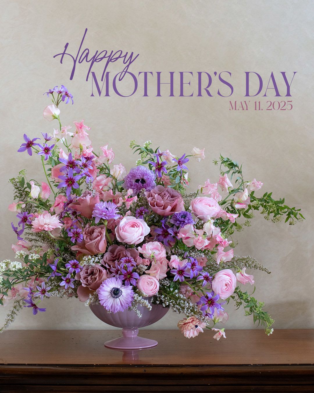Pink and purple floral arrangement in a lavender pedestal vase