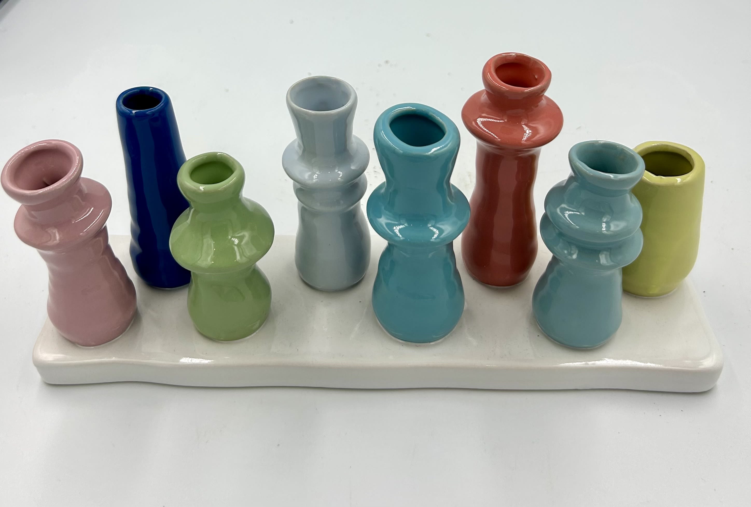 Colorful miniature ceramic vases arranged on a white tray