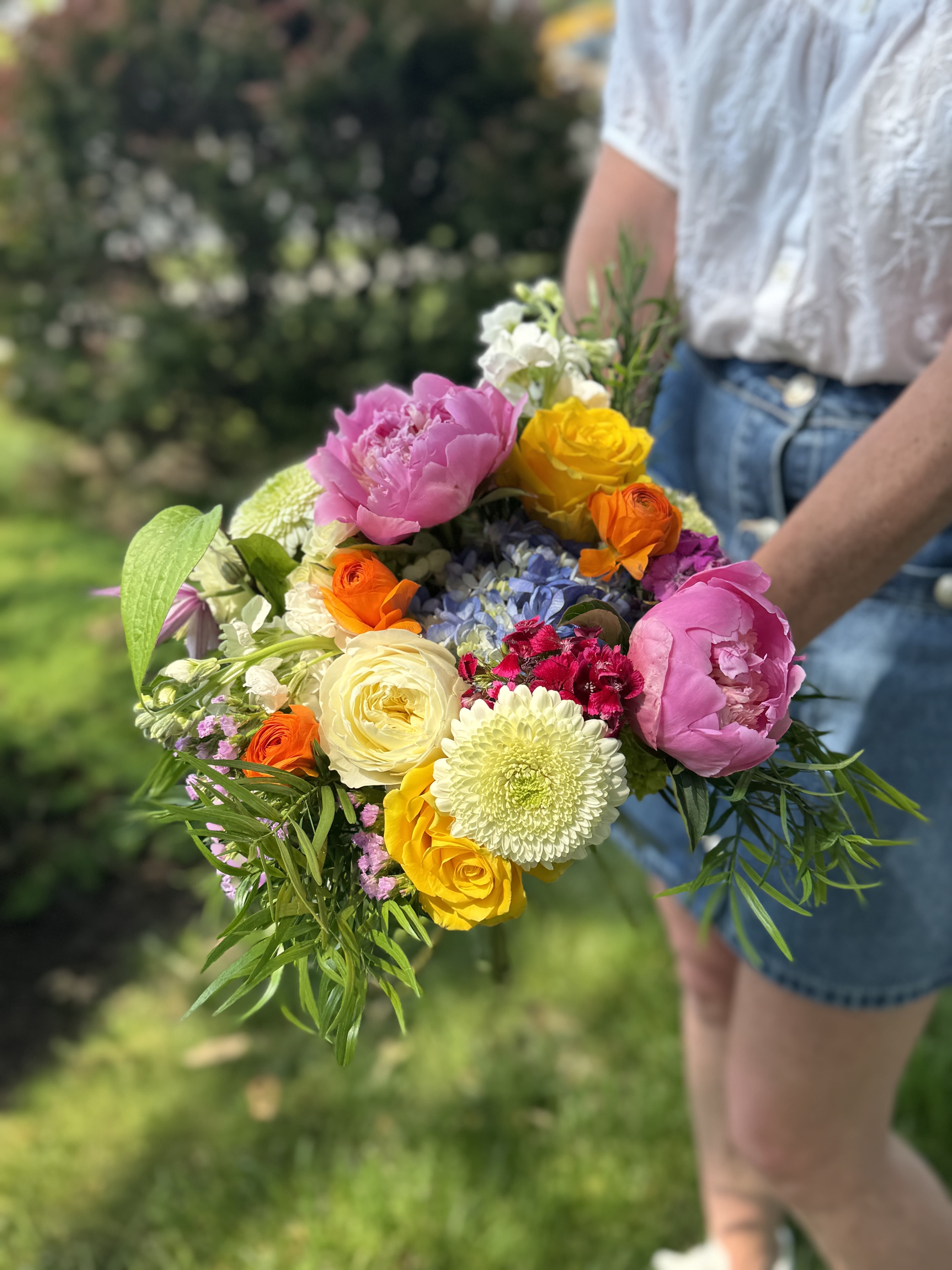 Handheld bouquet of pink, yellow, orange, and white flowers