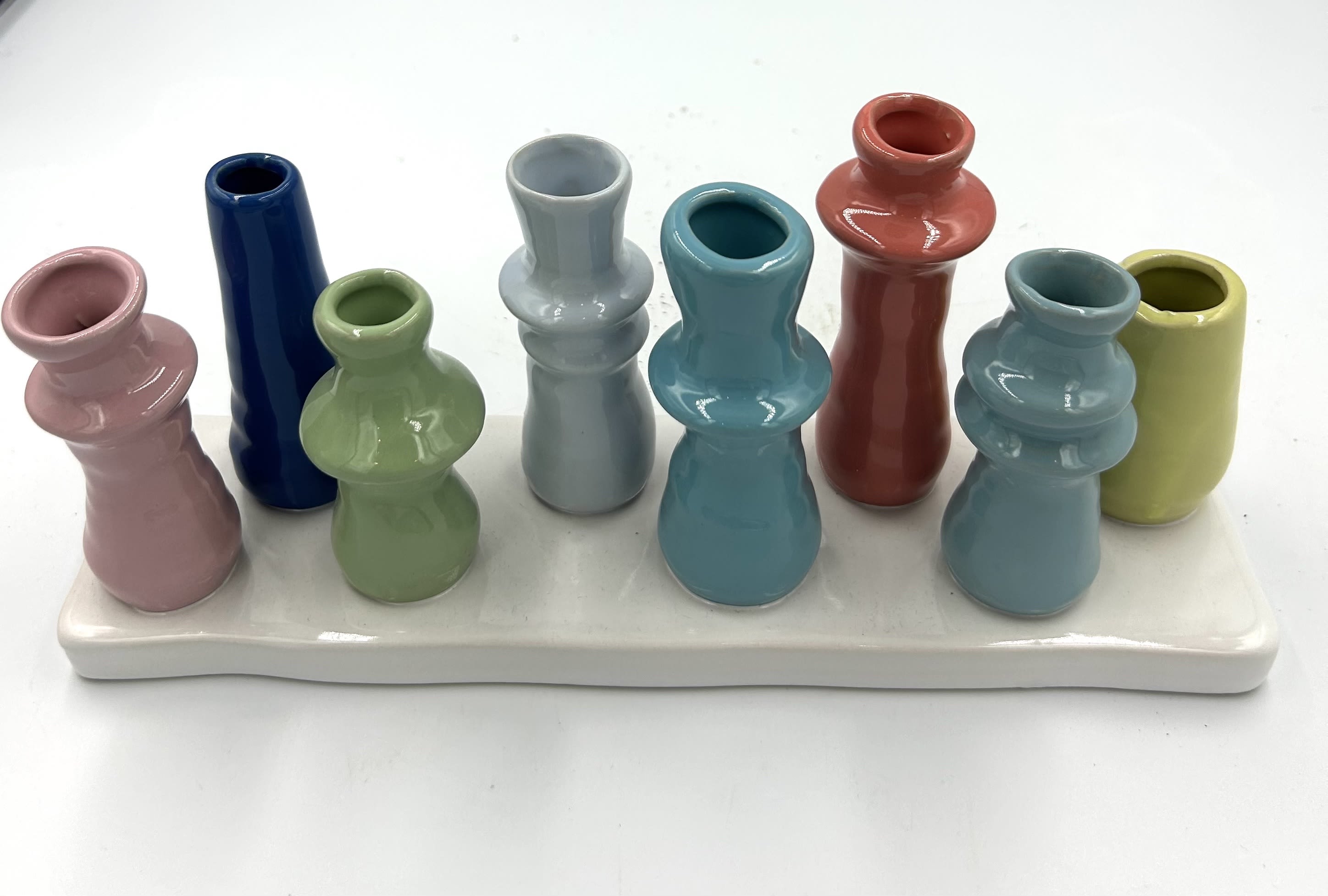 Colorful ceramic bud vases arranged on a white tray