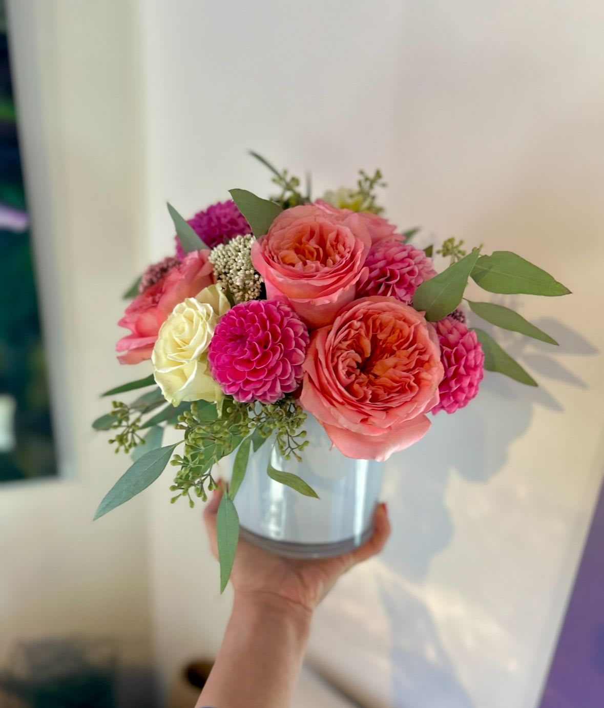 Pink and coral roses with magenta blooms in a silver vase