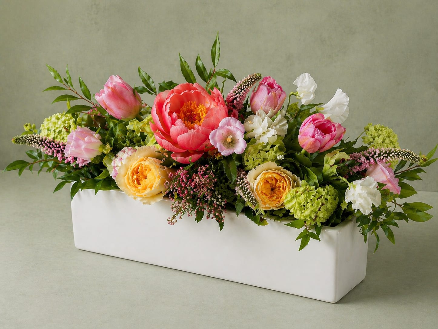 The Summer Entertaining Garden - A lush, garden-inspired arrangement designed with movement, texture, and fresh color. Featuring a standout dahlias or other seasonal stunner with soft ranunculus, buttery roses, delicate orlea, and vibrant green accents. Designed low and full in our signature rectangle white vessel, it’s a fresh, modern take on a just-picked garden—elevated, airy, and full of life. Vase size: 16" L x 4" H x 4"W-flowers well exceed vase size. Standard version= 1 arrangement, Deluxe=2 arrangements, Premium=3 arrangements. Perfect for parties!  We will use in season flowers and after peony season is over we will sub a similarly priced flower. 