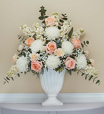 White and blush floral arrangement in a white pedestal vase