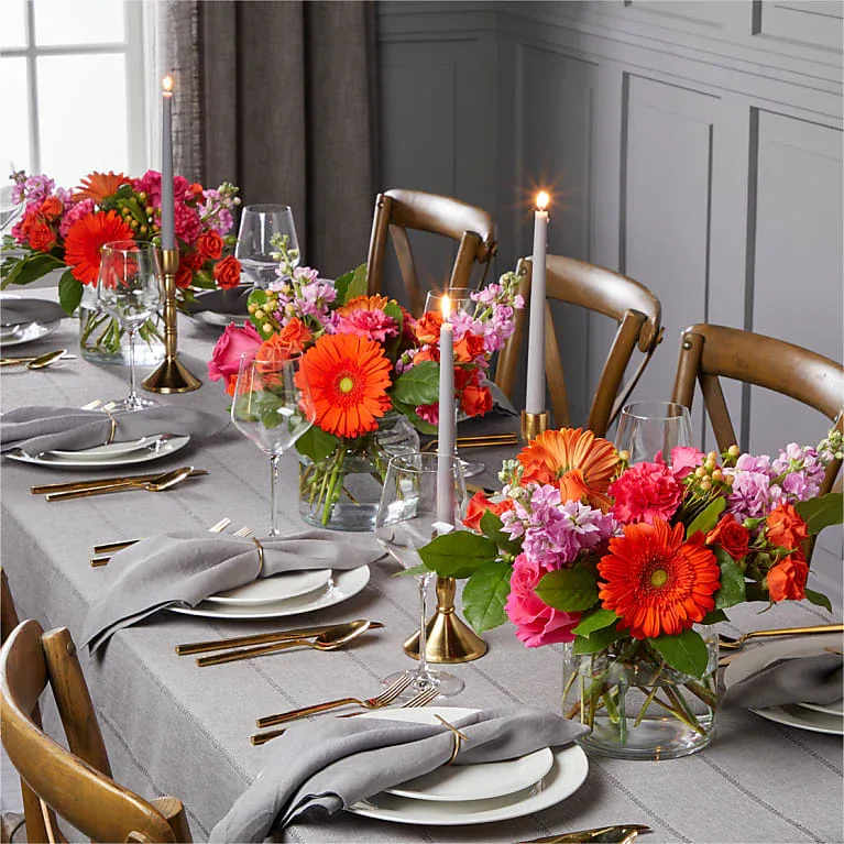 Bright mixed flower centerpieces on a set dining table with candles