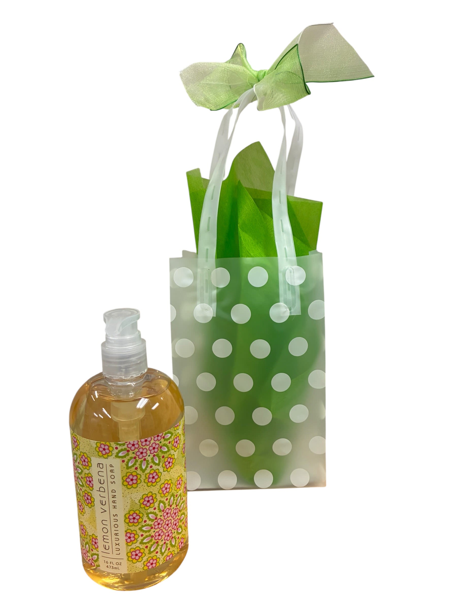 Lemon Verbena Soap - A fresh, spring-ready gift set that feels handcrafted and joyful-this Lemon Verbena Soap makes a lovely thank-you or small-occasion present for someone who appreciates bright, clean scents. The product is a flower-arrangement-adjacent gift set ideal for hostess gifts, teacher appreciation, or a cheerful pick-me-up; it pairs especially well with green-and-white or pastel floral arrangements for seasonal gifting.  Presented in a translucent green polka-dot gift bag with white ribbon handles and a pale green bow, the set includes bright green tissue paper and a clear pump bottle labeled "lemon verbena luxurious hand soap" with a floral-patterned label. Accents of white, yellow and soft pink in the packaging give it a springlike, casual charm. Ready to gift as-is-no extra wrapping needed-this compact set fits easily alongside an arrangement or on its own for a thoughtful, fragrant surprise.