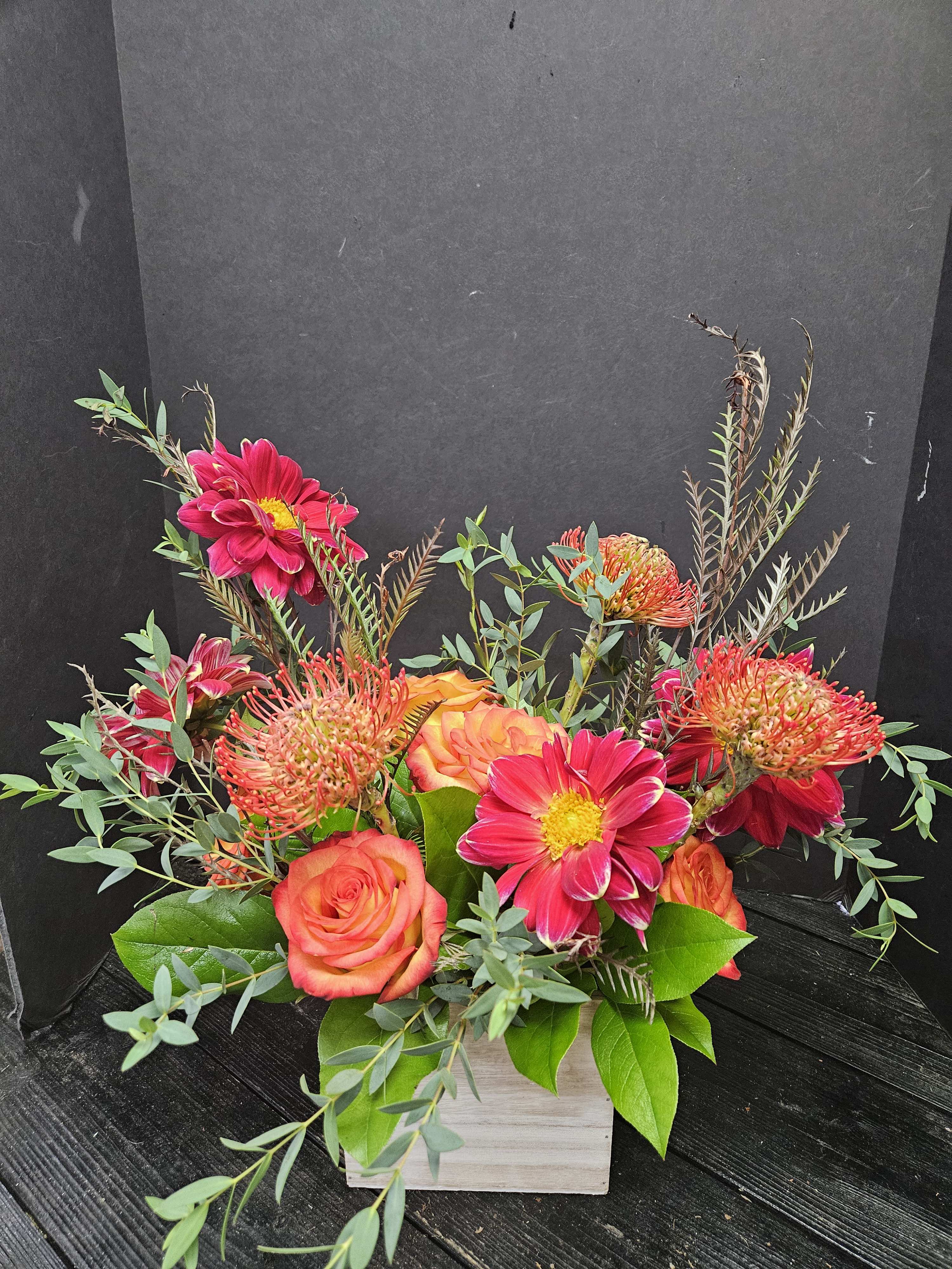 Bright pink and orange flowers arranged in a white wooden box