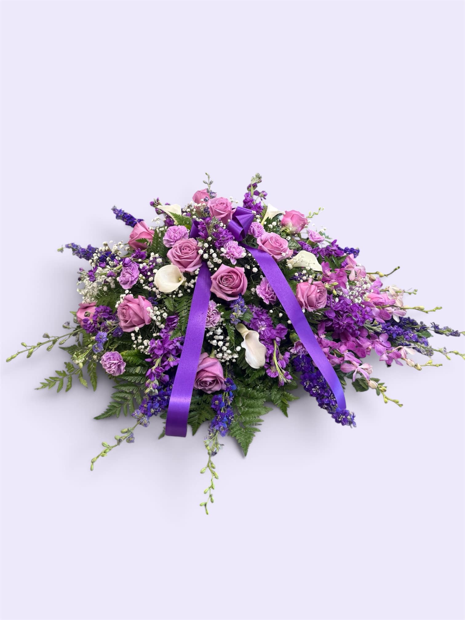 Purple and pink floral casket spray with ribbon accents
