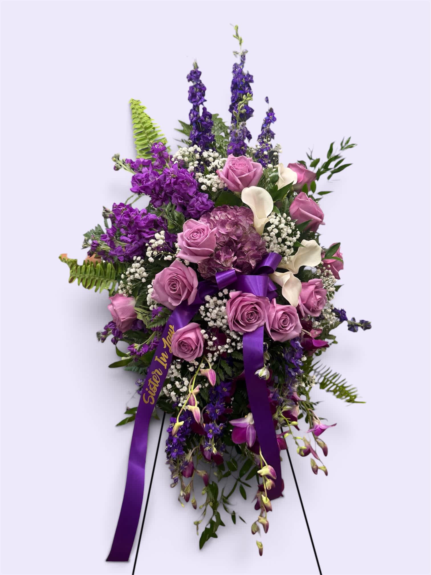 Standing floral spray with purple and pink flowers on a ribboned easel