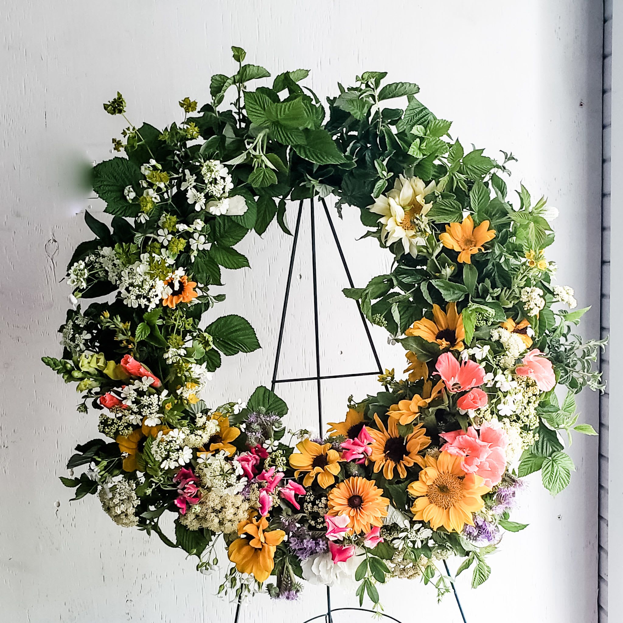 Large floral wreath with mixed blooms on a black stand