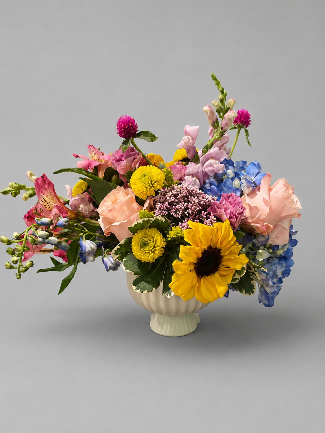 Colorful mixed flower arrangement in a cream vase