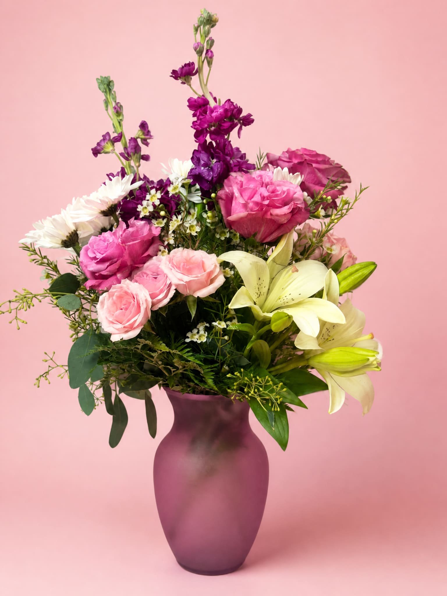 Pink and purple bouquet with lilies and roses in a purple vase