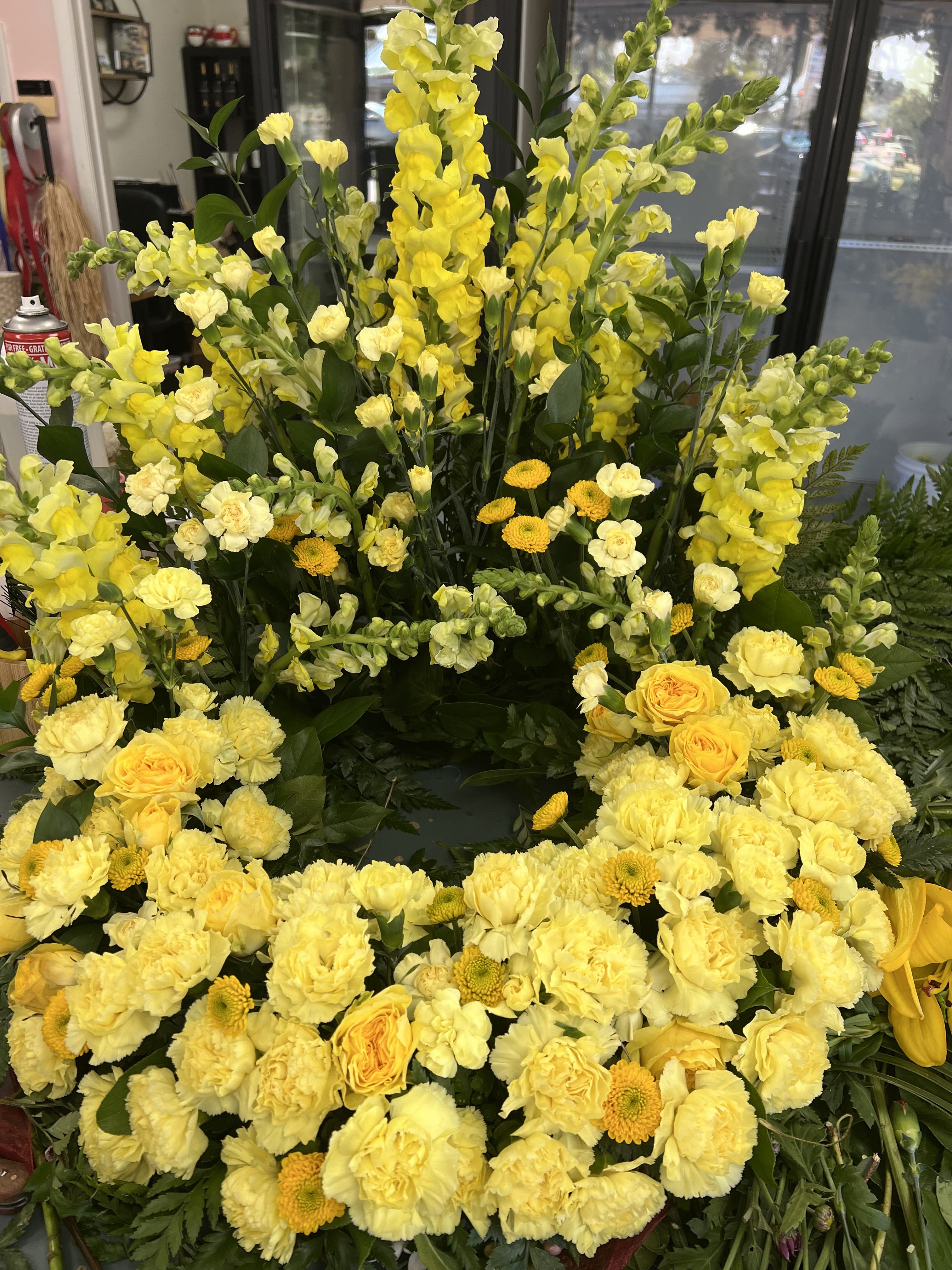 Large yellow floral wreath with roses, carnations, and snapdragons