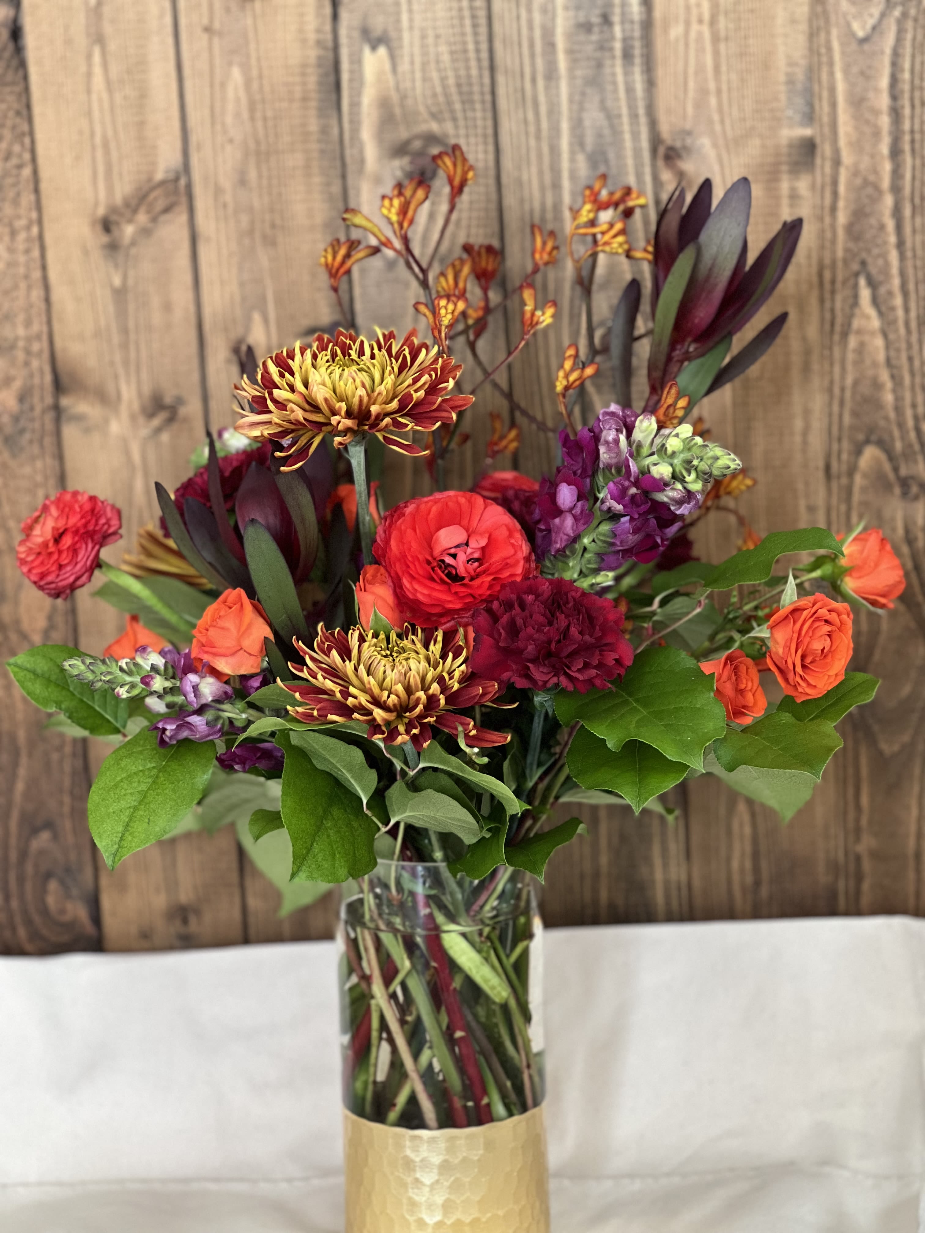 Mixed bouquet in a clear vase with orange, red, and purple blooms
