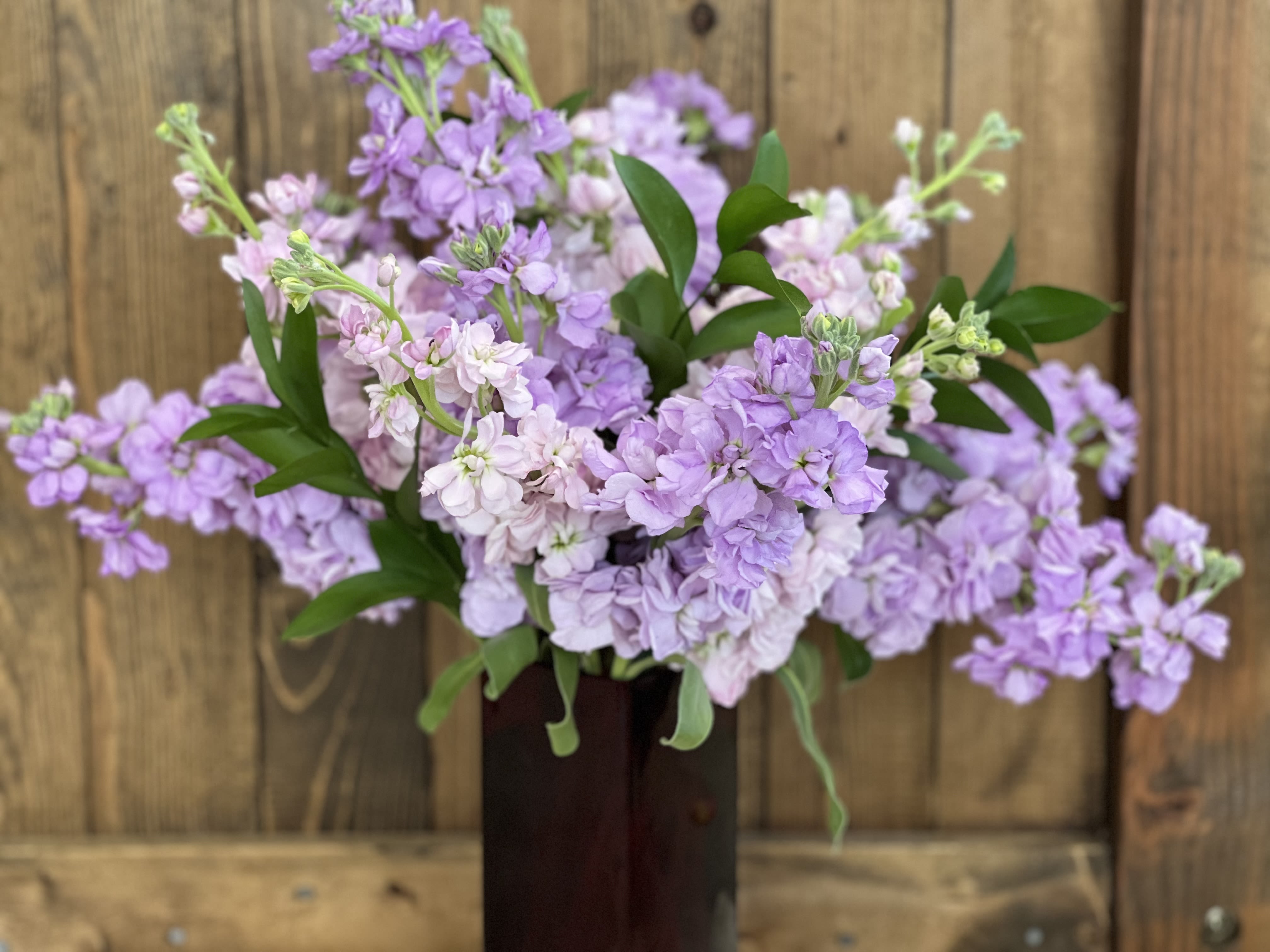 Lavender and pale pink flowers in a dark vase