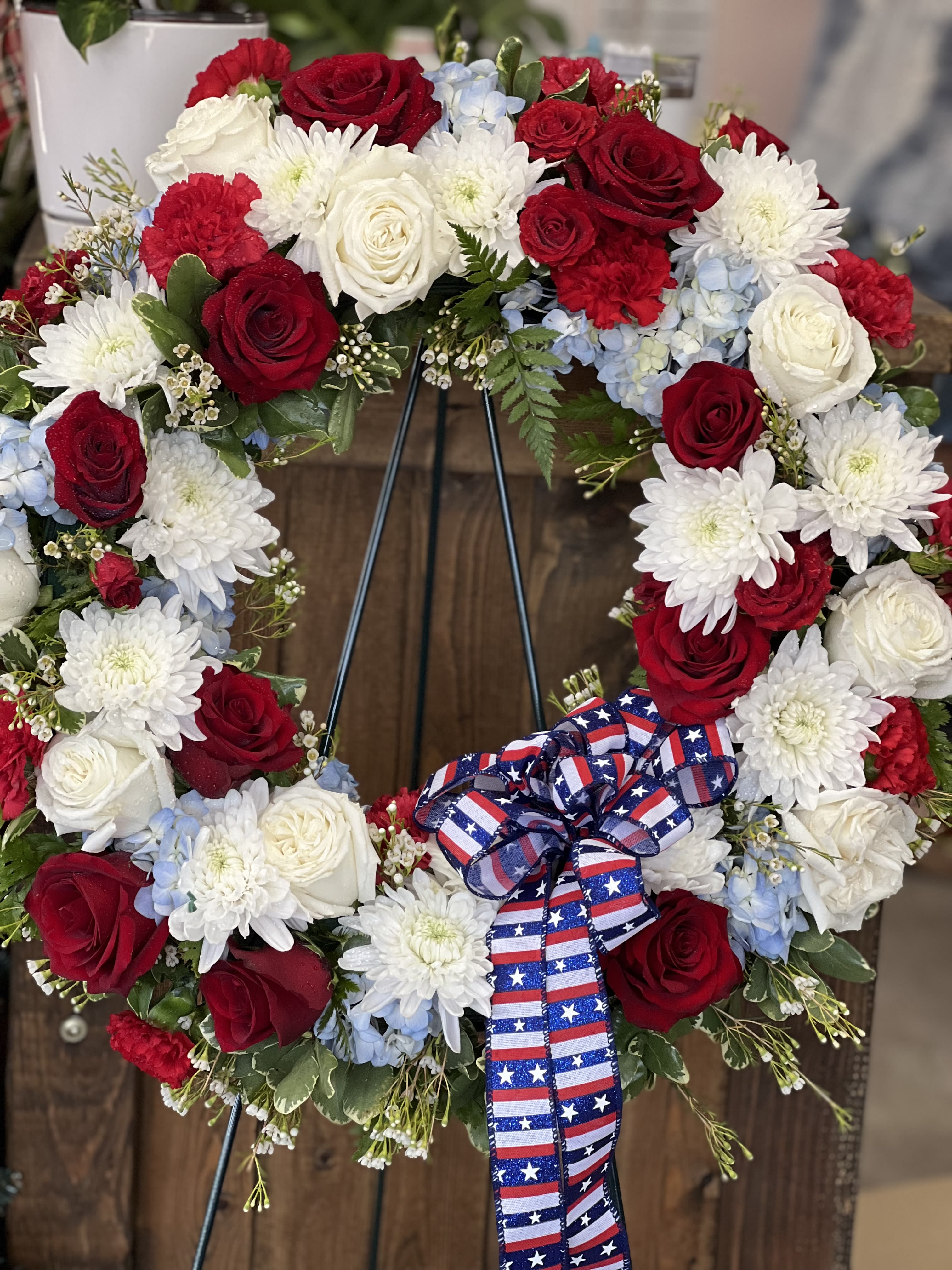Red, white, and blue floral wreath with a patriotic ribbon bow