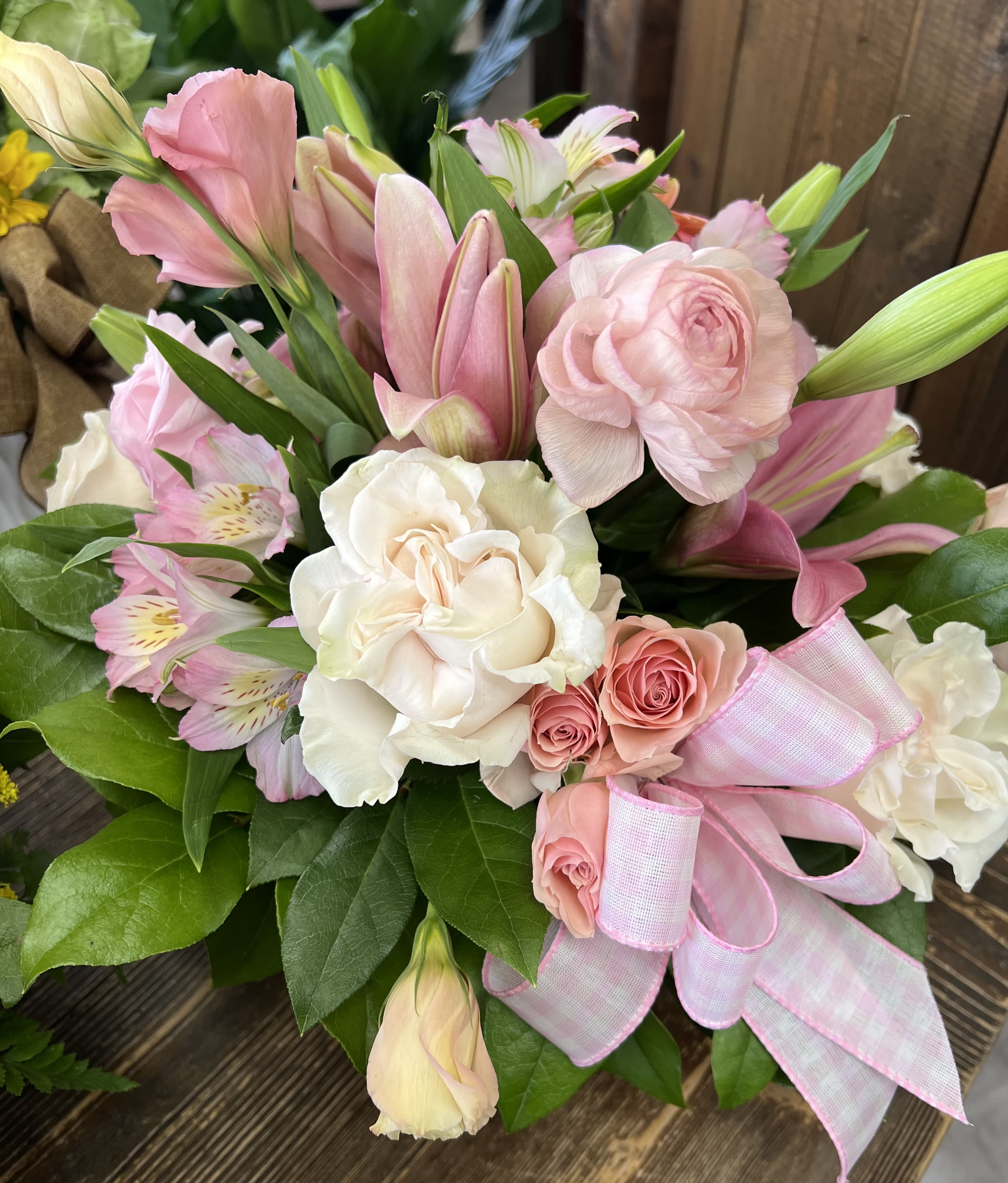 Pink and white bouquet with roses, lilies, and a ribbon bow