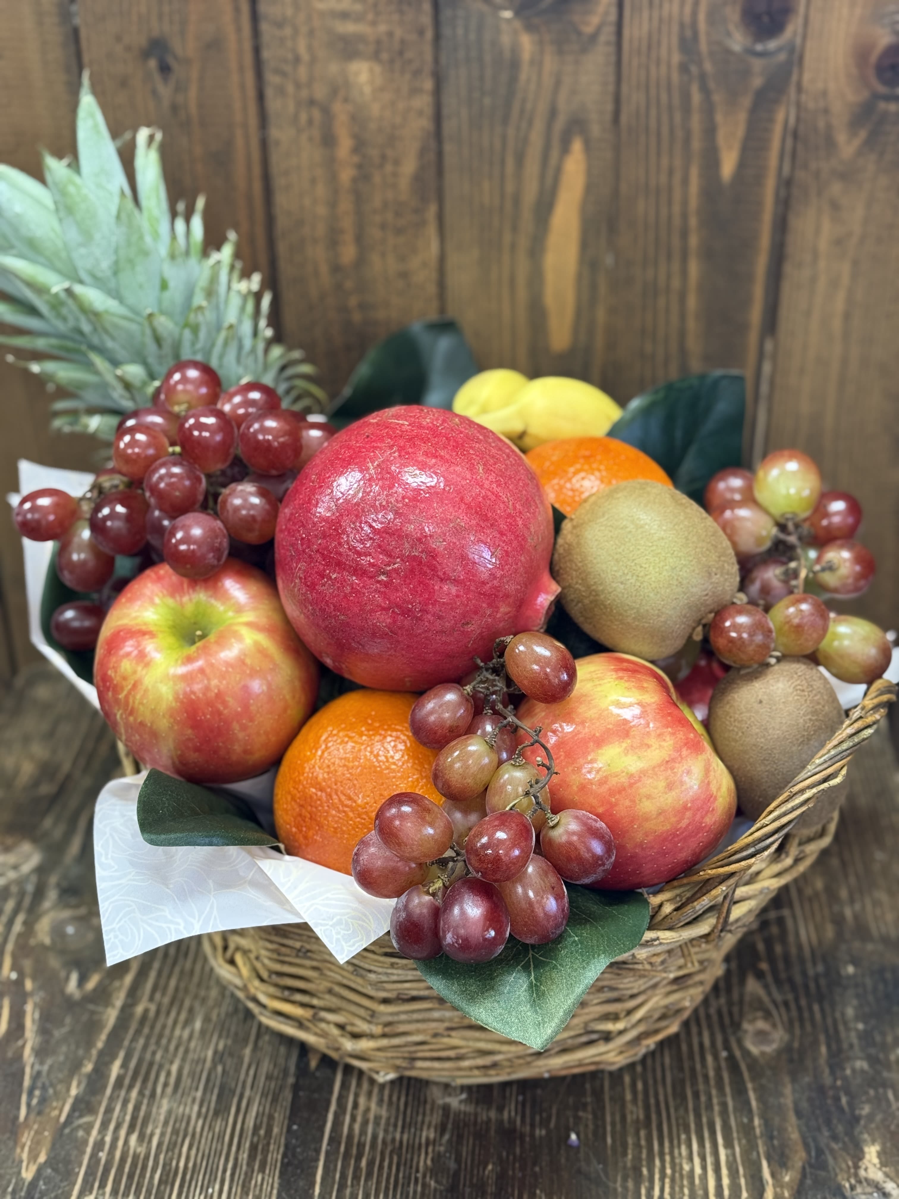 Fruit basket with apples, grapes, kiwi, oranges, and a pineapple