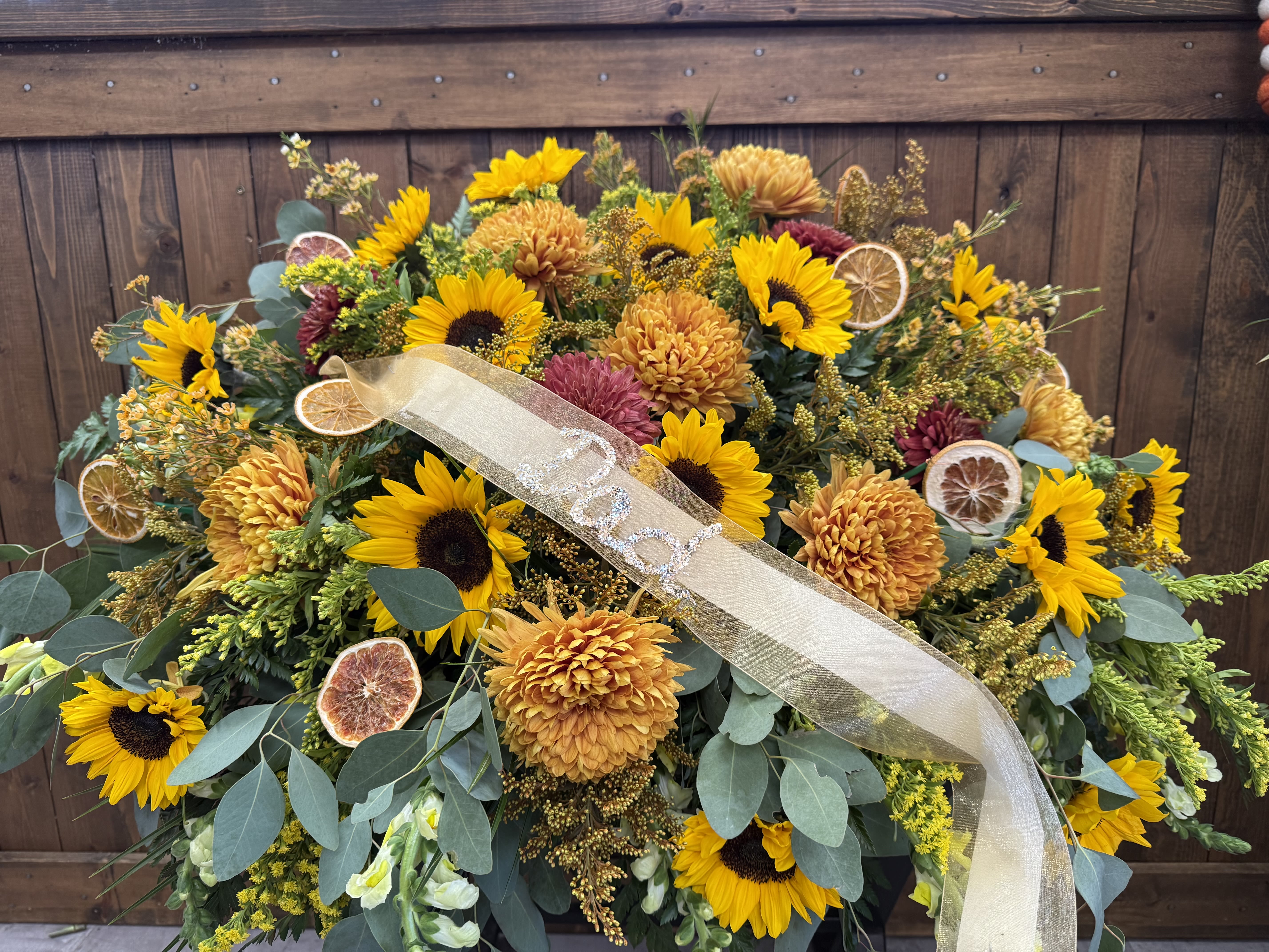 Large sunflower and chrysanthemum arrangement with a ribbon and dried citrus slices