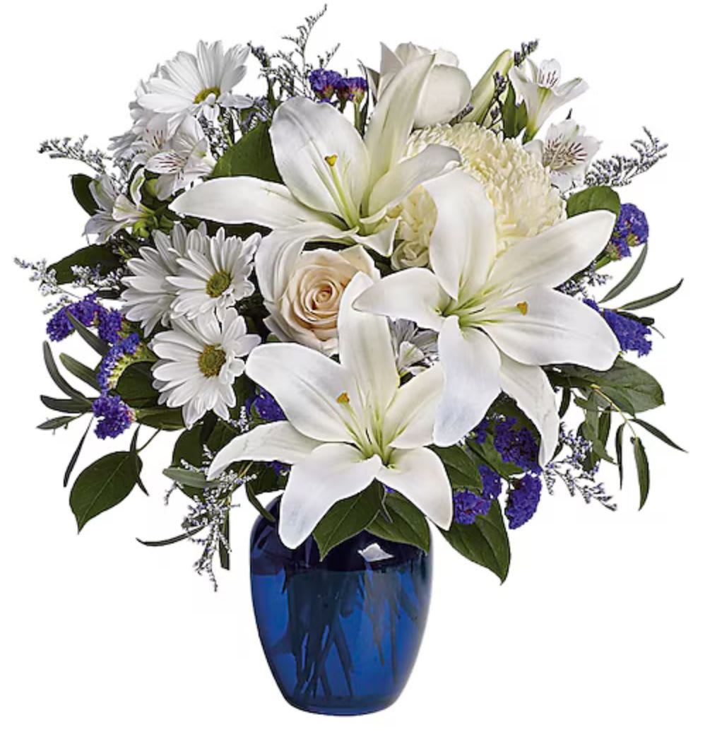 White lilies and daisies in a blue glass vase