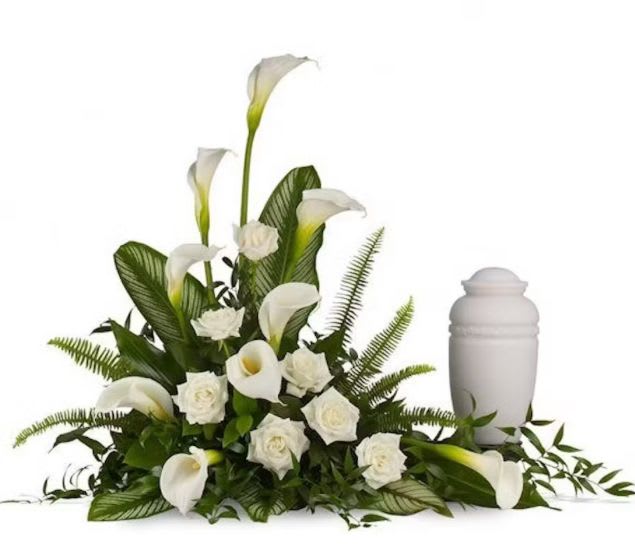 White calla lilies and roses arranged beside a white urn